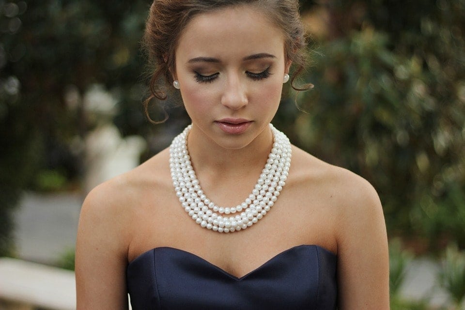 Girl holding pearl necklace for a formal event
