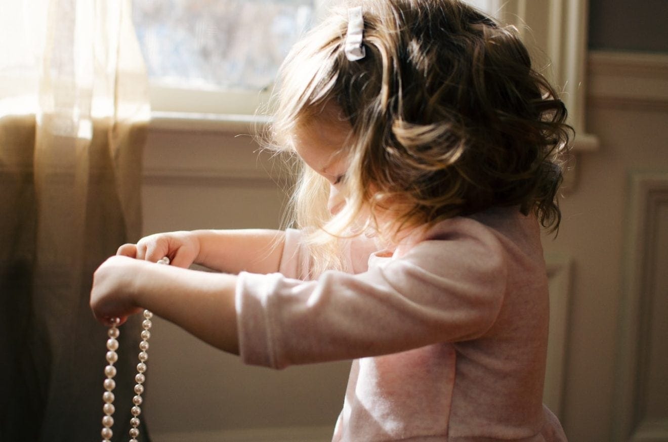 Little girl holding pearl necklace