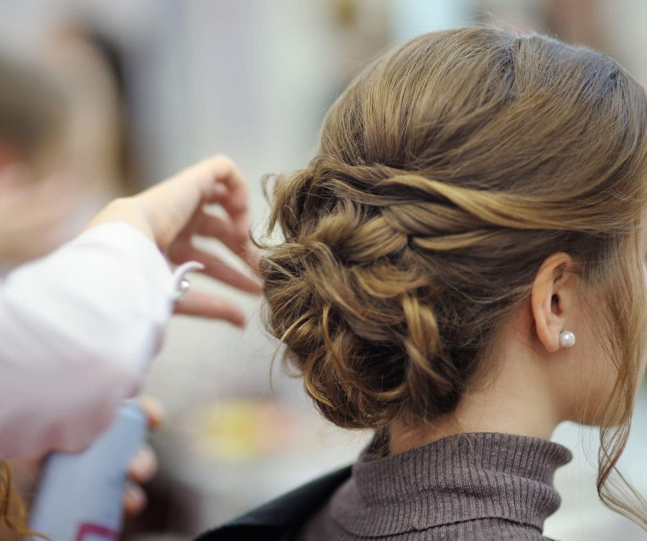 Young woman/bride wearing pearl stud getting her hair done before wedding or party.
