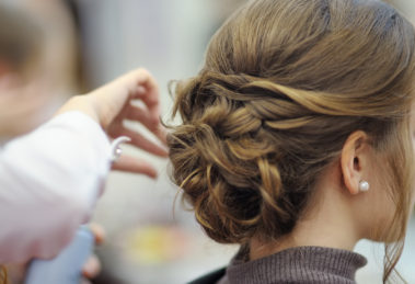 Young woman/bride wearing pearl stud getting her hair done before wedding or party.