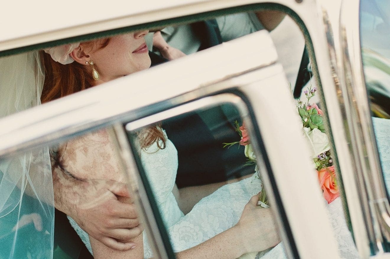 Bride wearing pearl necklace sitting in a car going to her wedding