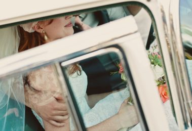 Bride wearing pearl necklace sitting in a car going to her wedding